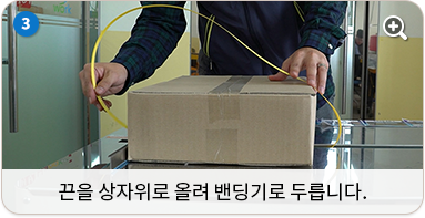 끈을 상자 위로 올려 밴딩기로 두릅니다.