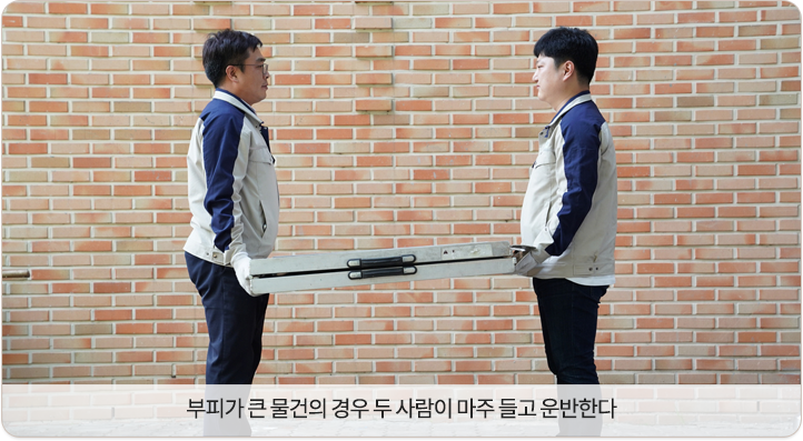 두 사람이 양쪽에서 화물 끝을 잡고 운반.