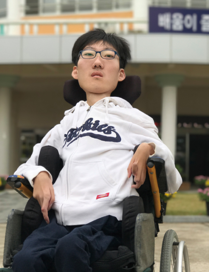 박경택학생이 학교 앞에서 휠체어에 앉아 있는 모습