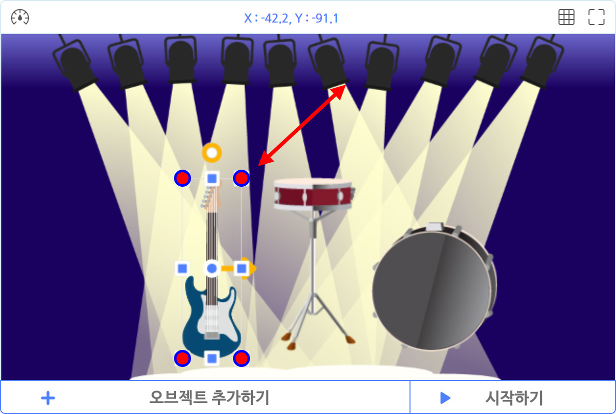 이미지. 실행화면의 스크린샷, 무대위에 기타와 드럼이 있다. 기타 오브젝트가 선택되어 있고, 양쪽 화살표가 그려져 있고 1번 표시가 되어 있다.  가운데에 노란색 화살표가 오른쪽을 향해 그려져 있다.